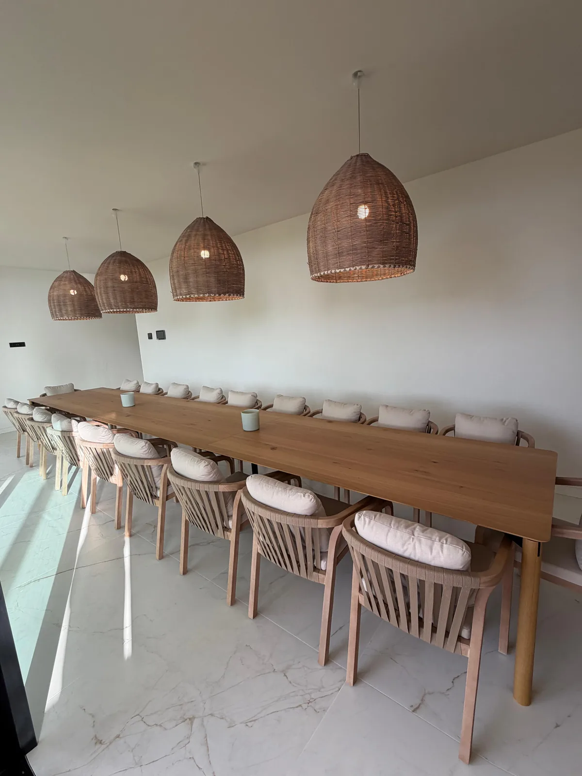 Dining table under woven pendant lights