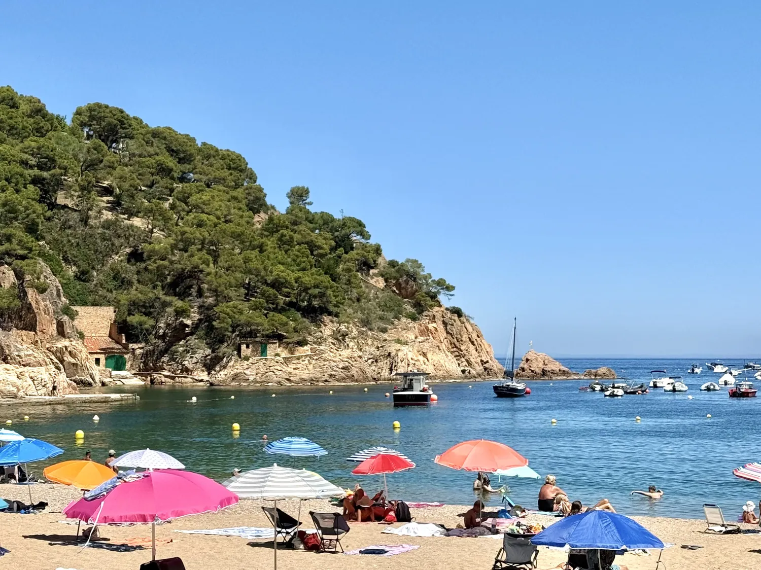 Tamariu beach with parasols and boats