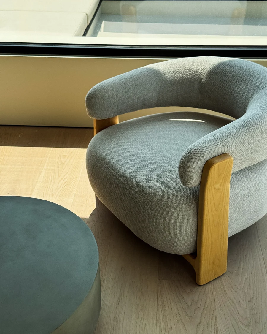 An armchair by the glass, oak floor and the terrace beyond