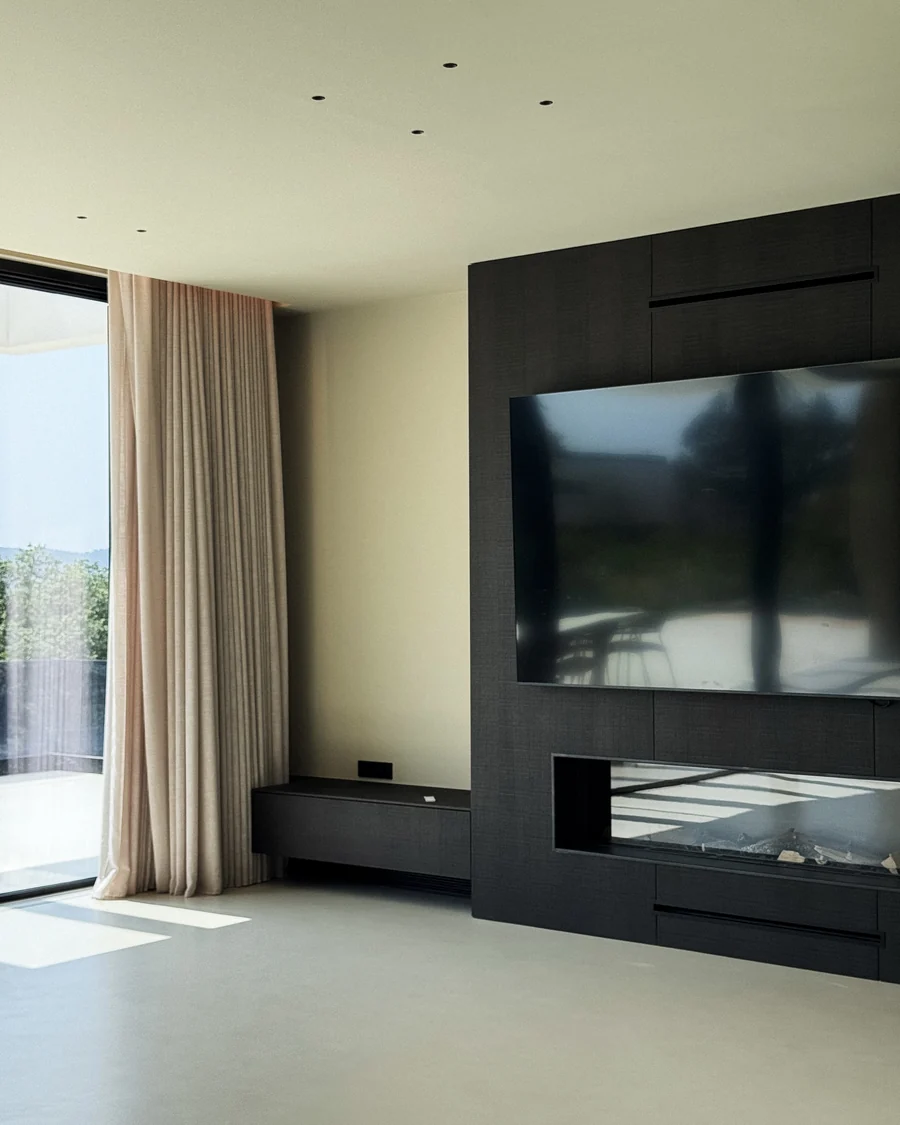 The living room wall in dark timber with a recessed fireplace and screen