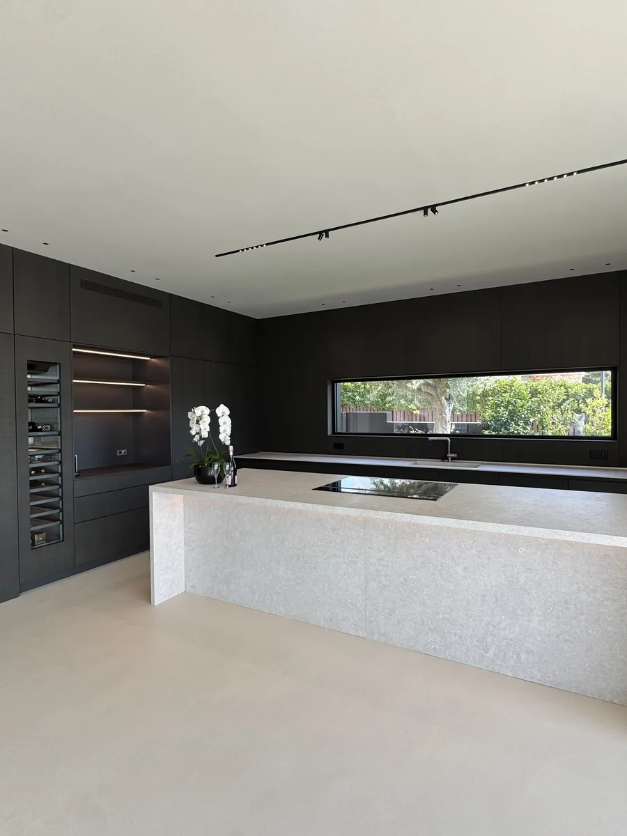 Kitchen with a stone island and dark joinery