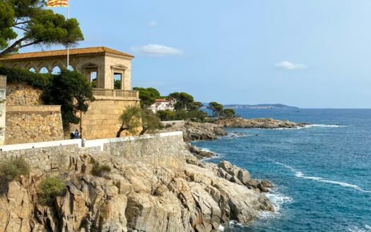 Rocky Costa Brava shoreline with a stone viewpoint pavilion above the sea