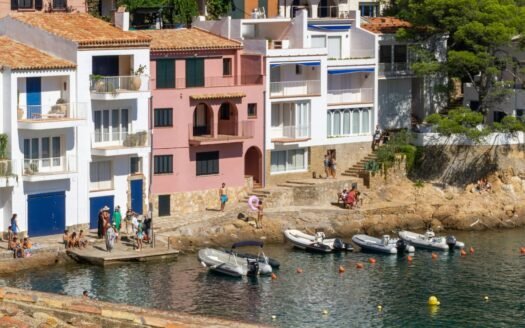Whitewashed and pink seafront houses above a cove on the Costa Brava, Spain