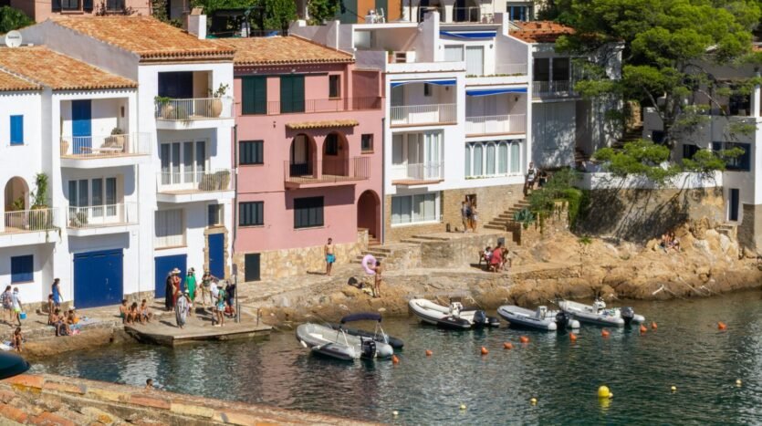 Whitewashed and pink seafront houses above a cove on the Costa Brava, Spain